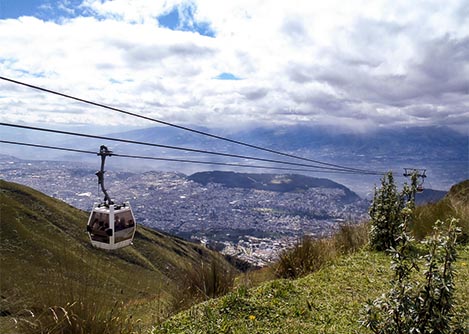 A TeleferiQo cable car on a hillside with the city of Quito visible in the distance.