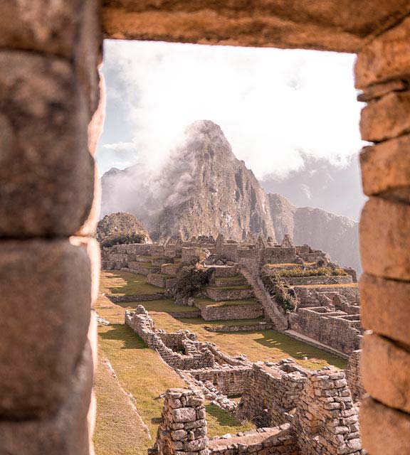 Huayna Picchu mountain and the ruins of Machu Picchu as seen from a stone window.